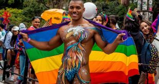 Max Souza desfila com o corpo pintado com as cores do arco-íris na Parada do Orgulho LGBT+
